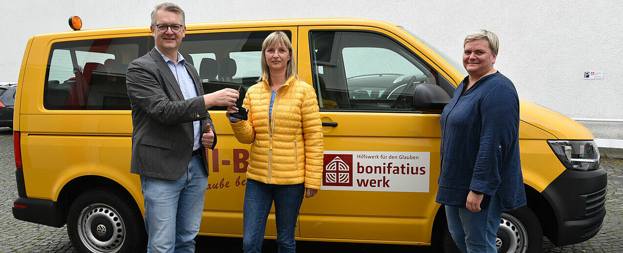 Thomas Twents, Bereichsleiter Projektverwaltung im Bonifatiuswerk, übergibt Daiga Ročkus (Mitte) und Inese Motte vom Malteser Hilfsdienst die Schlüssel für den BONI-Bus. (Foto: Simon Helmers)