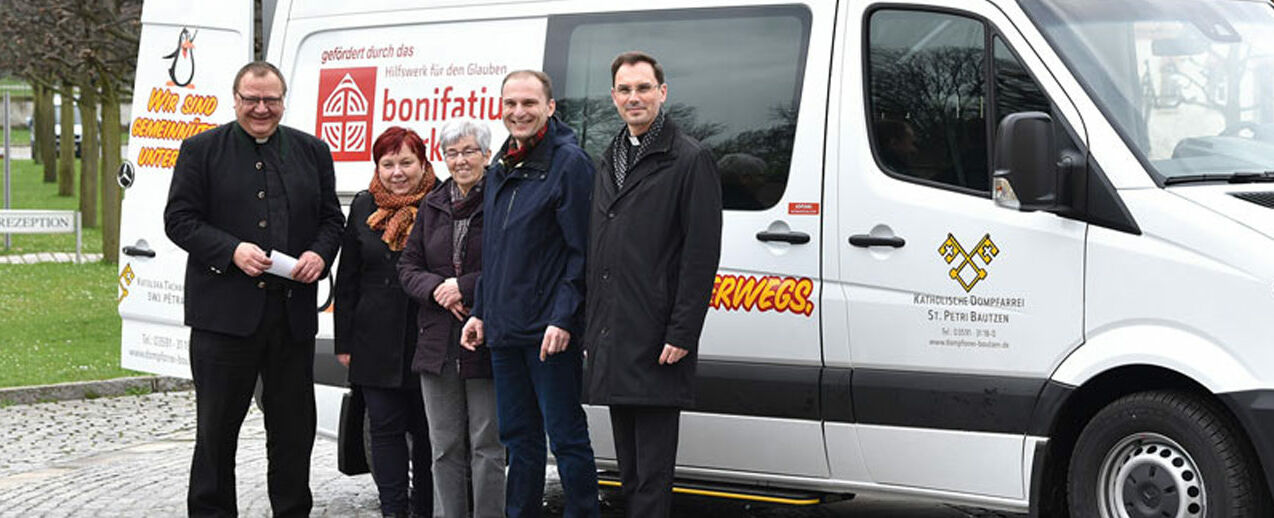Dompfarrer Veit Scapan aus Bautzen (links) und Diözesanadministrator Andreas Kutsche (rechts) mit dem Team des Pastoralbusses auf dem Hof des Bischof‐Benno‐Hauses in Schmochtitz bei Bautzen. 