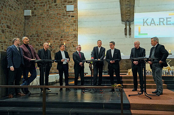 Bei der Talkrunde im Bild v.l. Landrat Jens Womelsdorf, Vorsitzender der Isalmischen Gemeinde Prof. Dr. Bilal Farouk El-Zayat, Architekt Max Reith, Leiter KA.RE. connect Martin Stanke, Propst Dr. Volker Mantey, Bischof Dr. Michael Gerber, Pfarrer Markus Blümel, Pfarrer Franz Langstein, Oberbürgermeister Dr. Thomas Spies. (Foto: KA.RE. Marburg)