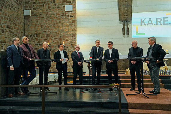 Bei der Talkrunde im Bild v.l. Landrat Jens Womelsdorf, Vorsitzender der Isalmischen Gemeinde Prof. Dr. Bilal Farouk El-Zayat, Architekt Max Reith, Leiter KA.RE. connect Martin Stanke, Propst Dr. Volker Mantey, Bischof Dr. Michael Gerber, Pfarrer Markus Blümel, Pfarrer Franz Langstein, Oberbürgermeister Dr. Thomas Spies. (Foto: KA.RE. Marburg)