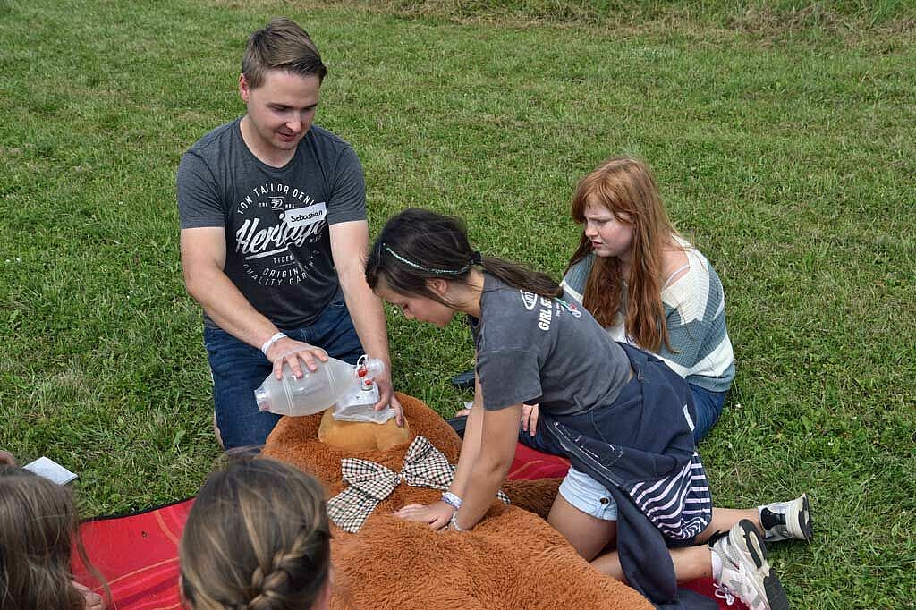 Sebastian und Luise (11) machen Milena (11) vor, wie eine Herzdruckmassage funktioniert. (Foto: Simon Helmers)