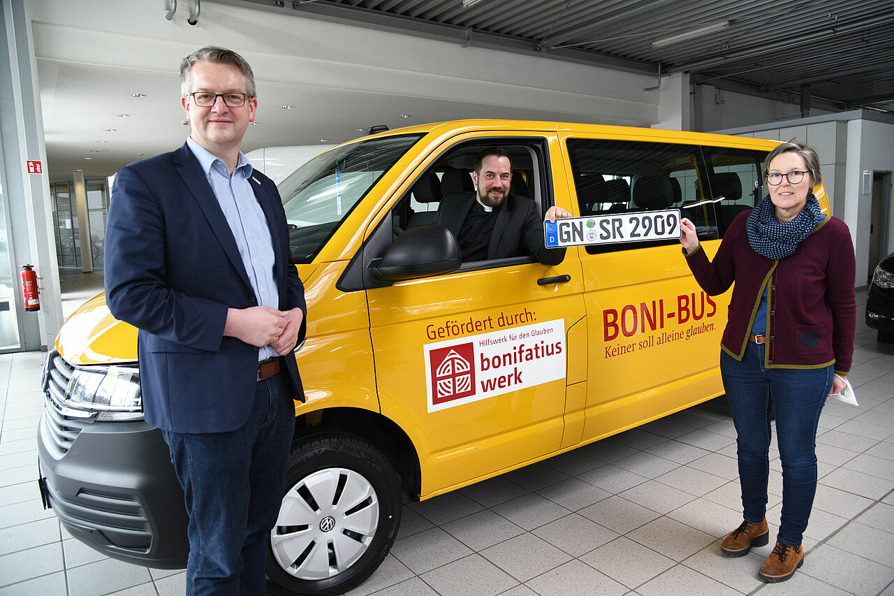 Kaplan Andre Lemmer und Regina Saase aus dem Bistum Fulda präsentieren das bedeutungsträchtige Kennzeichen des neuen BONI-Busses. Thomas Twents vom Bonifatiuswerk freut sich darüber. (Foto: Theresa Meier)