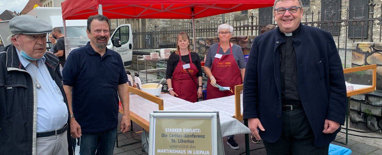 Ulrich Gelhard (v. l.), Eugen Riese, Msgr. Georg Austen und ehrenamtliche Bäckerinnen am Waffelstand auf dem Paderborner Wochenmarkt. Foto: J. Birwer