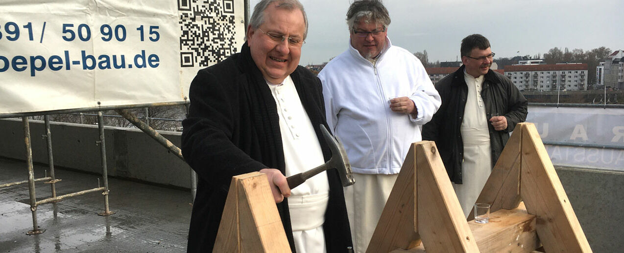 Pater Prof. Dr. Clemens Dölken O.Praem., Prior des Priorates Magdeburg, schlägt den Nagel in den Balken ein. Dahinter P. Michael Stern und P. Ulrich Weiß, beide ebenfalls aus dem Priorat. (Foto: St.-Norbert-Stiftung/Andrea Leinenbach)