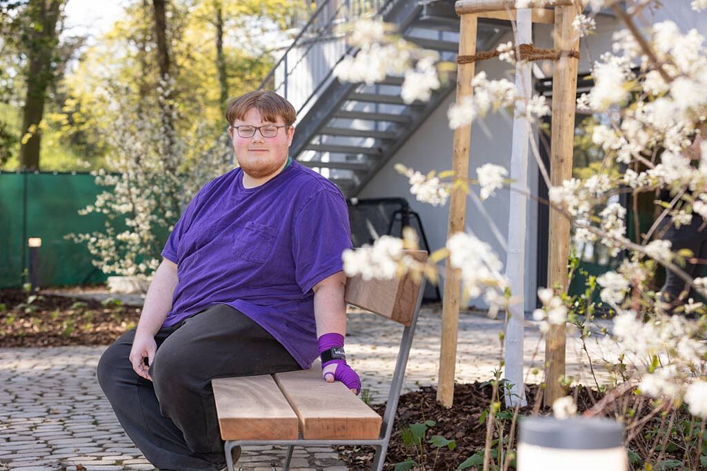 Bewohner Nico sitzt auf einer Bank im Garten des Hauses Martha. . Foto: Hartmut Salzmann)