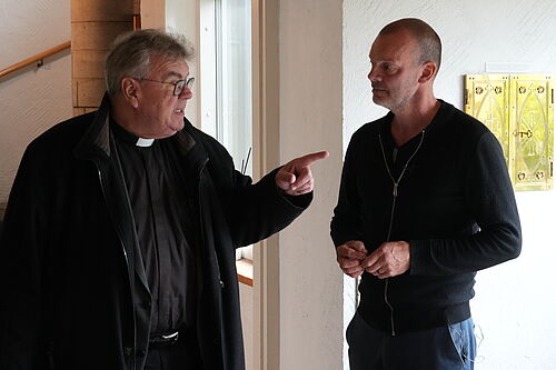 Bonifatiuswerk-Generalsekretär Msgr. Georg Austen mit dem Pfarrgemeinderatsvorsitzenden Eilif Brimheim, der das geplante barrierefreie Projekt erklärt (v.l.). Foto: Pfr. Martin Geistbeck