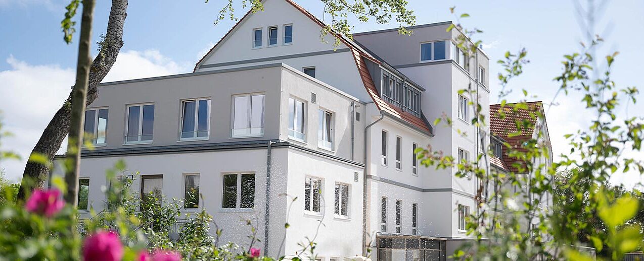 Idyllischer Blick durch die Gartenflora auf den modernen Gebäudekomplex Haus Meeresstern. (Foto: Offizialat Vechta / Johannes Hörnemann)
