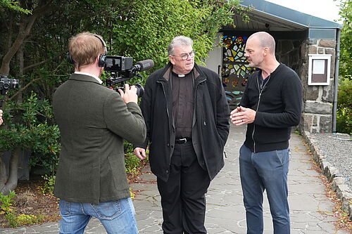 Bonifatiuswerk-Generalsekretär Msgr. Georg Austen mit dem Pfarrgemeinderatsvorsitzenden Eilif Brimheim, der das geplante barrierefreie Projekt erklärt (v.l.). Foto: Pfr. Martin Geistbeck