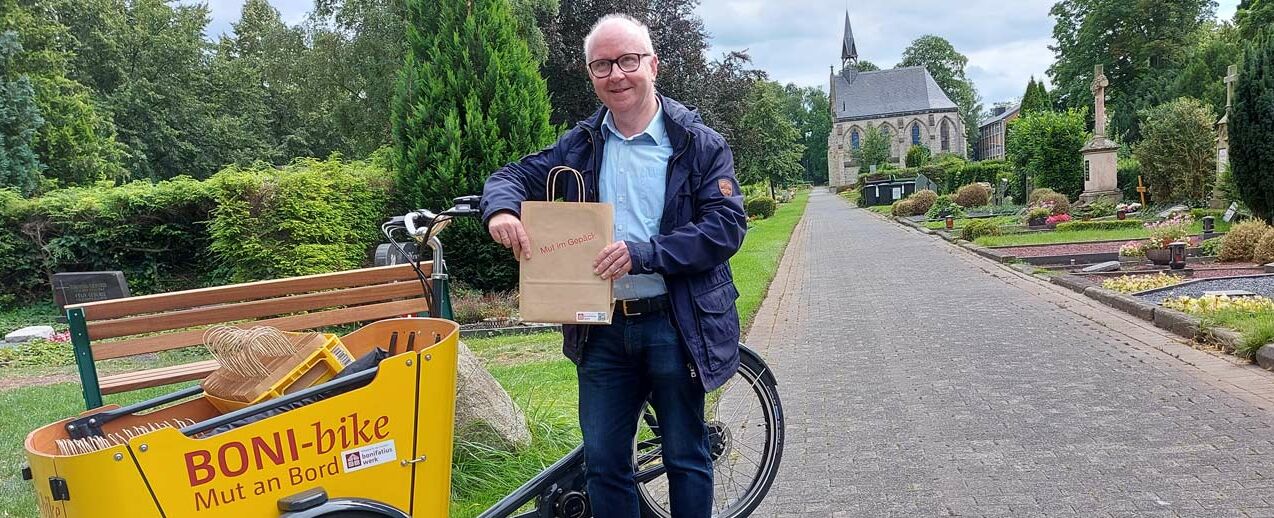 Dr. Dirk Lenschen, Mitarbeiter des Bonifatiuswerkes mit dem Boni-Bike auf dem Ostfriedhof in Paderborn. (Foto: Katrin Sijbom)