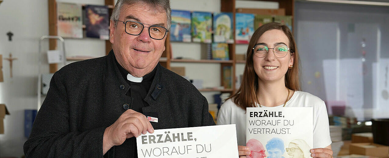 Bonifatiuswerk-Generalsekretär Monsignore Georg Austen und Bonifatiuswerk-Referentin Eva Dreier stehen mit dem Plakat zwischen den Materialmappen, die zur inhaltlichen Vorbereitung des Diaspora-Sonntags an alle katholischen Gemeinden in Deutschland verschickt werden. Foto: Matthias Band