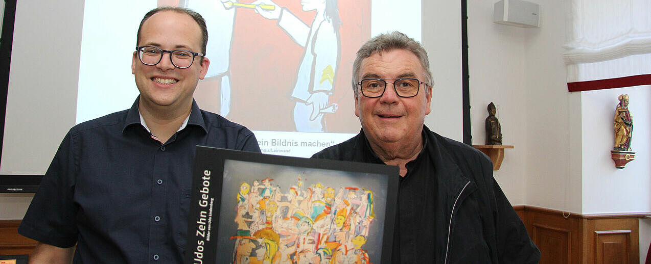 Daniel Born (links) und Msgr. Georg Austen zeigen den Ausstellungskatalog mit den Werken von Udo Lindenberg. (Foto: Matthias Band) 