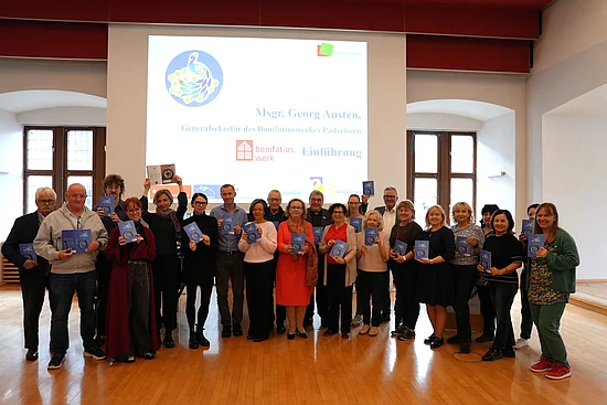 Monsignore Austen überreicht das neue Bonifatiuswerk-Kochbuch "Taste the North" den Helfern des Netzwerktreffens. (Foto: Marcus Thielking)
