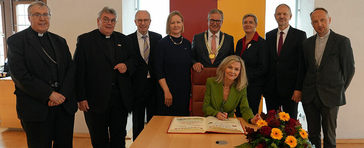Trugen sich auf Einladung von Bürgermeister Michael Dreier (Mitte) in das Goldene Buch der Stadt Paderborn ein (von links): Bischof Czeslaw Kozon, Monsignore Georg Austen, Manfred Müller, Marika Linntam, Veronika Wand-Danielsson, Alda Vanaga, Giedrius Puodžiūnas sowie Bischof Viktors Stulpins. (Foto: Simon Helmers)