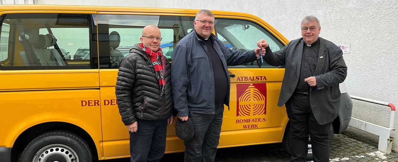 Monsignore Georg Austen (rechts) übergibt den Bonibus an Pfarrer Rinalds Stankevic (Mitte) und Sandris Stepanovs. (Foto: Bonifatiuswerk/Marius Thöne)