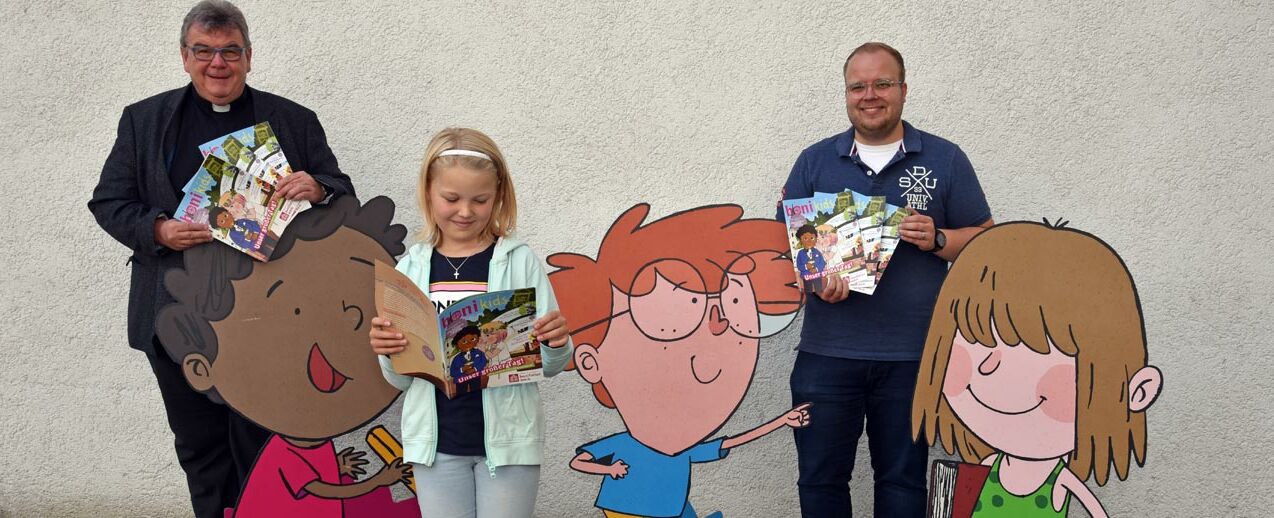 Monsignore Georg Austen, das Kommunionkind Marie Scholz und Julian Heese, Referent für Missionarische und diakonische Pastoral im Bonifatiuswerk, präsentieren die Sonderausgabe der bonkids zur Erstkommunion. (Foto: Sr. Theresita M. Müller)