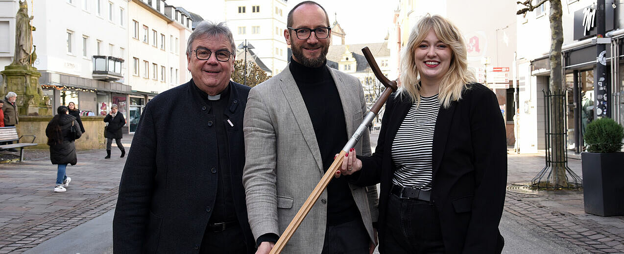 Dr. Sebastian Neugebauer vom DBW Essen (Mitte) freut sich über den Pilgerstab, der ihn künftig bei der Arbeit begleiten wird. Überreicht wurde er von Bonifatiuswerk-Generalsekretär Monsignore Georg Austen und Marisa Grummich, Referentin im Hilfswerk. (Foto: Theresa Meier)