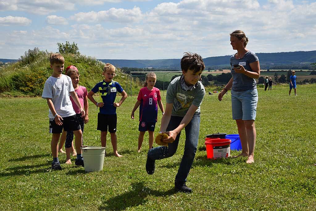 Kerstin Werner (rechts) stoppt die Zeit, während die Kinder das Wasser von einem Eimer zum anderen transportieren. Gerade läuft Leonard (12) mit dem Schwamm. (Foto: Simon Helmers)