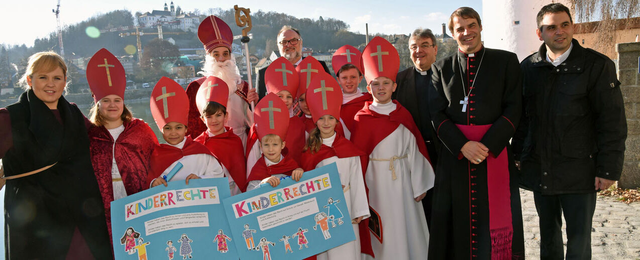 Acht Kinderbischöfe aus der Grund- und Mittelschule St. Nikola in Passau haben gemeinsam mit dem heiligen Nikolaus, Maite Kelly (links), Passaus Oberbürgermeister Jürgen Dupper (Mitten hinten), Monsignore Georg Austen (dritter von links), Bischof Stefan Oster und dem stellvertretenden Landrat, Raimund Kneidinger, die Weihnachtsmannfreie Zone des Bonifatiuswerkes in Passau eröffnet. Foto: Patrick Kleibold