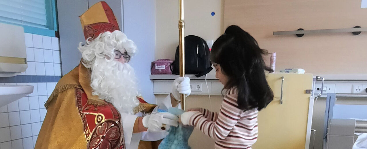 Der Nikolaus überreicht Najwah Wanidi in der Kinderklinik St. Louise einen Nikolaussocken. (Foto: Lena Schmidt, St. Vincenz-Kliniken Salzkotten + Paderborn)