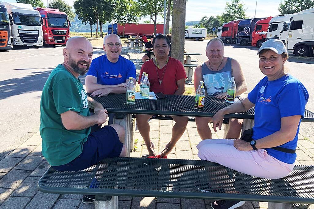 	Das Team der Lenkpause im Gespräch mit LKW-Fahrern auf einem Rastplatz. Foto: Betriebsseelsorge Bodensee-Hohenzollern, Erzdiözese Freiburg