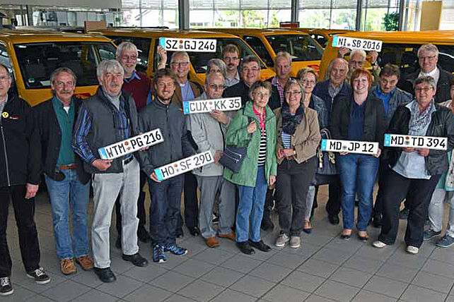 Monsignore Georg Austen (10.v.l.) übergab in Paderborn an die Vertreter von sieben Kirchengemeinden und Institutionen aus den Bistümern Hildesheim, Magdeburg und Osnabrück und dem Erzbistum Bamberg einen rapsgelben BONI-Bus. Foto: Lena Reiher