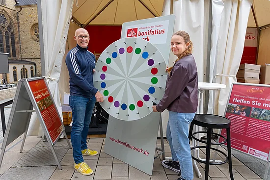 Melissa Hall (Sachbearbeitung Fundraising) und Matthias Band (Bereichsleiter Kommunikation) sorgen dafür, dass es am Infostand des Bonifatisuwerkes rund läuft. Foto: Hartmut Salzmann