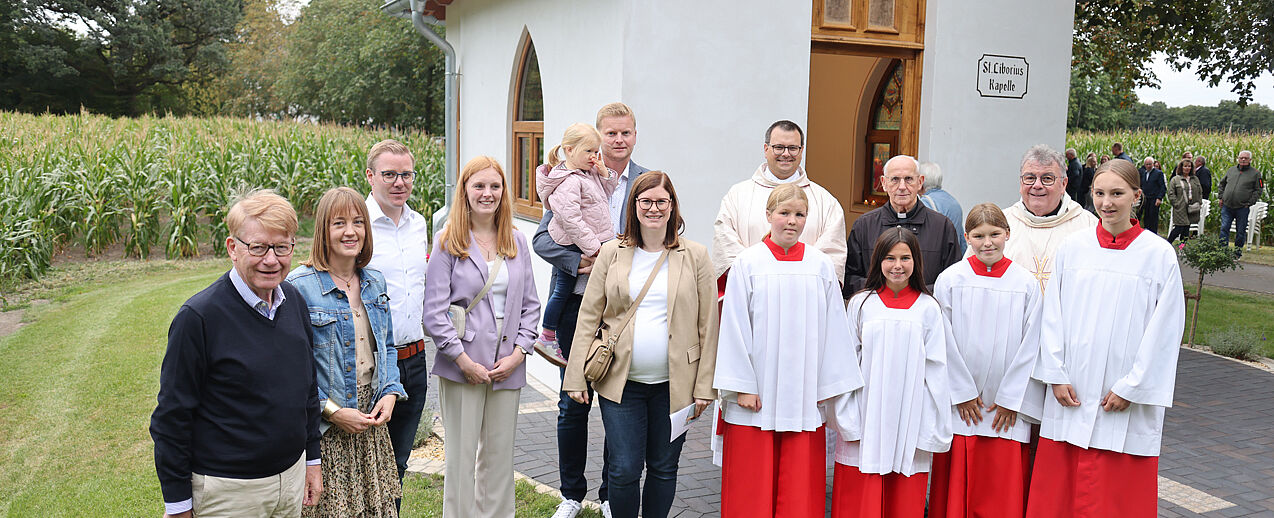 Freuen sich über die neue Kapelle (von links): Rainer Krukenmeier, Juliane Driller, Martin Krukenmeier, Katharina Sander, Marcel Brake mit Malina,  Christina Krukenmeier-Brake, Pastor Dr. Manuel Klashörster, Nele Echterhoff, Sophie Pape, Pastor Georg Romanski, Bonifatiuswerk-Generalsekretär Monsignore Georg Austen und Svea Göke. (Foto: Bernhard Hoppe-Biermeyer)