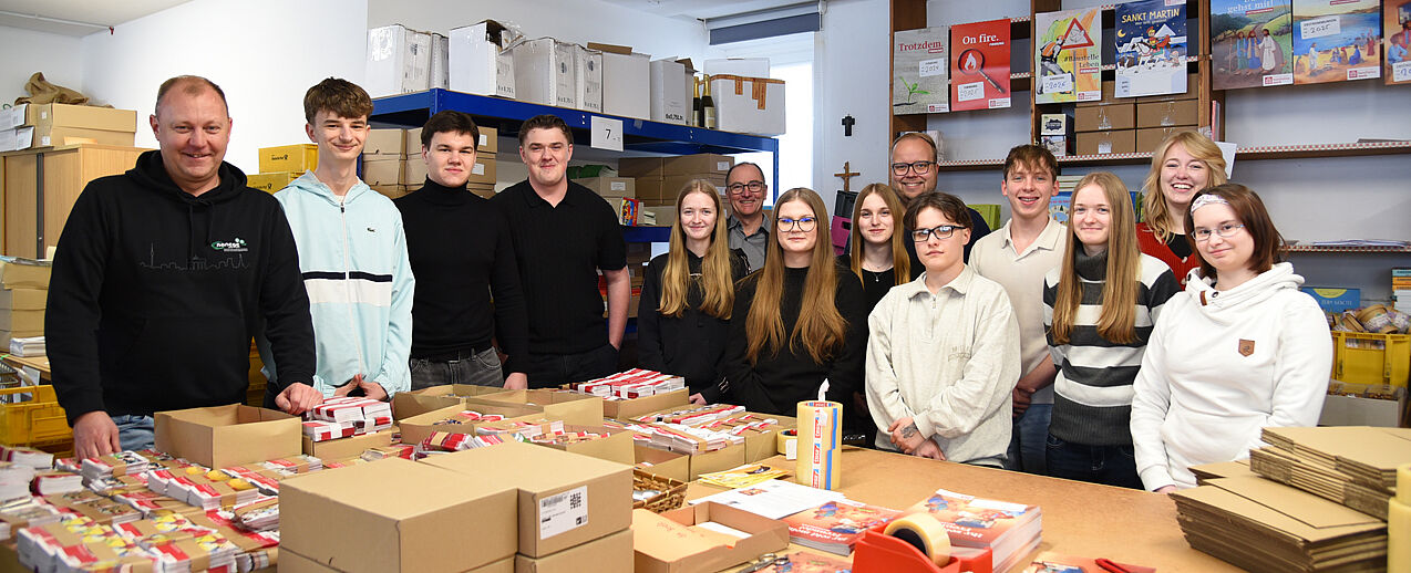 Zehn Schüler aus Berlin freuen sich auf die praktischen Erfahrungen in Paderborn. Hier werfen sie einen Blick in den Versand des Bonifatiuswerkes. Mit dabei sind Klassenlehrer Robert Lisiecki (l.), Dr. Till Moog, Präsident des Rotary Clubs Paderborn Stadt+Land (6.v.l.) und vom Bonifatiuswerk: Julian Heese (6.v.r.) und Marisa Grummich (2.v.r.). (Foto: Theresa Meier)