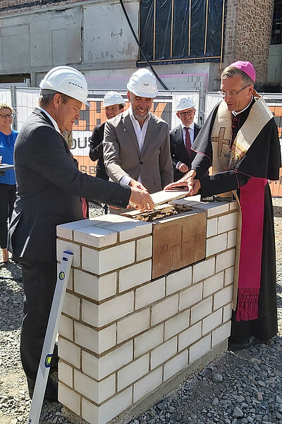 Oberbürgermeister Dr. Thomas Spies, Architekt Stephan Storch und Bischof Dr. Michael Gerber versiegeln unter den aufmerksamen Blicken von Karin Schoppet (Pfarrgemeinderat St. Peter und Paul), Dr. Martin Stanke (Hochschulpfarrer KHG Marburg) und Probst Dr. Volker Manthey die Zeitkapsel. (Foto: Claudia Plociennik)