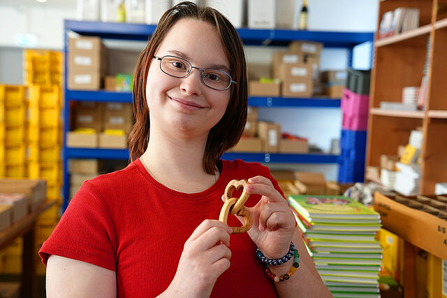 Die 18-jährige Skyler aus Berlin hat ihr Lieblingsprodukt im Versand des Bonifatiuswerkes gefunden: zwei verbundene Holzherzen. (Foto: Theresa Meier)