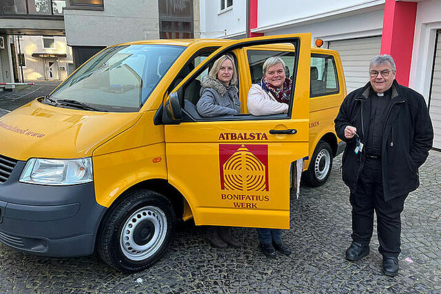 Monsignore Georg Austen übergibt den Bonibus an Daiga Rockus und Inese Motte (Mitte) von den lettischen Maltesern. (Foto: Bonifatiuswerk/Marius Thöne)