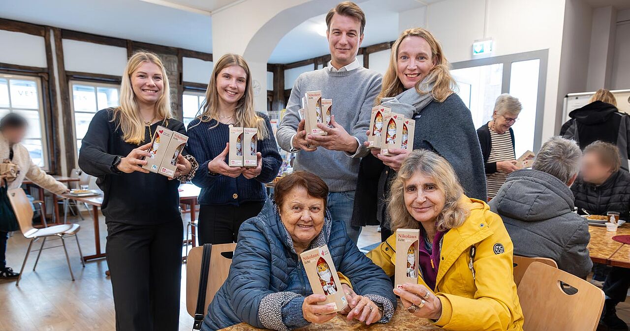 120 Bonifatiuswerk-Schokonikoläuse wurden jetzt an die Gäste der Padermahlzeit in Paderborn verteilt. Baftish Ballushi und Sulku Dallandyshe (vorne v.l.) freuten sich über die süße Überraschung. Mit im Bild: Cara Hennig, Lisa Möhring, Christopher Gladen (alle Wegener Massivhaus) sowie Katrin Füchtmann, Bereichsleitung Fundraising Bonifatiuswerk (hinten v.l.). Foto: Hartmut Salzmann
