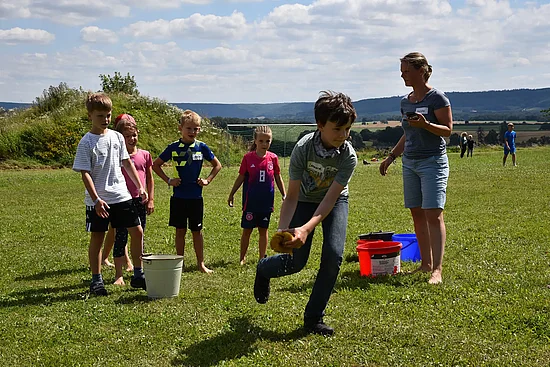 Kerstin Werner (rechts) stoppt die Zeit, während die Kinder das Wasser von einem Eimer zum anderen transportieren. Gerade läuft Leonard (12) mit dem Schwamm. (Foto: Simon Helmers)