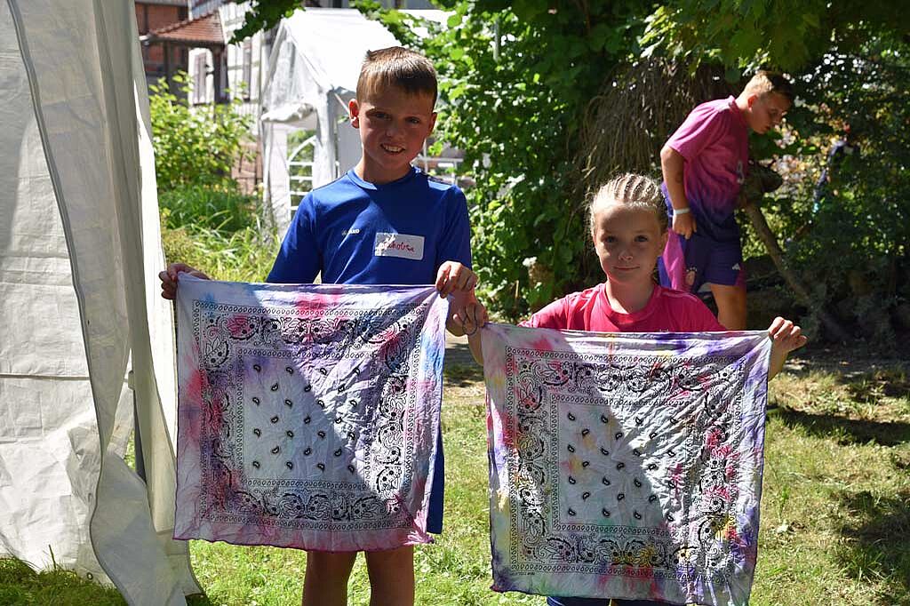 Jakob (10) und Greta (7) präsentieren ihre selbst eingefärbten Tücher, ehe diese zum Trocknen aufgehangen werden. (Foto: Simon Helmers)
