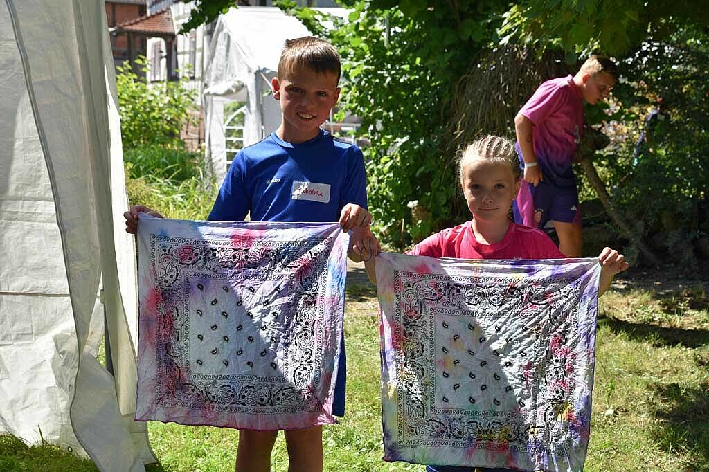 Jakob (10) und Greta (7) präsentieren ihre selbst eingefärbten Tücher, ehe diese zum Trocknen aufgehangen werden. (Foto: Simon Helmers)