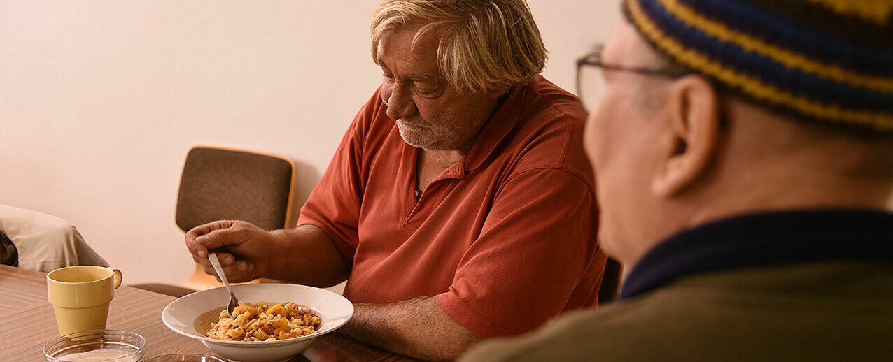 Pater Kalle Lenz (rechts) setzt sich während der warmen Mahlzeit gerne für ein Gespräch zu den Bedürftigen. (Foto: Pia Wittek)