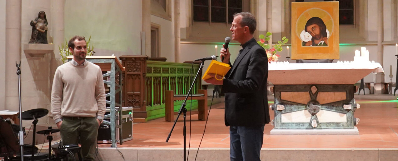 Pfarrer Martin Sinnhuber von der Gemeinschaft Emmanuel übergibt dem neuen Stelleninhaber Gunnar Sornek ein Bild des Heiligen Liudger (Foto: Emmanuel House Münster)