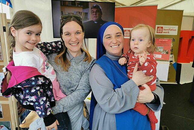 Katholikentagsbesucherin Stephanie Hummel aus Erfurt mit ihren Töchtern Antonia (6) und Lucia (10 Monate), die von der blauen Schwester M. Coeli auf den Arm genommen wird. (Foto: Matthias Band)