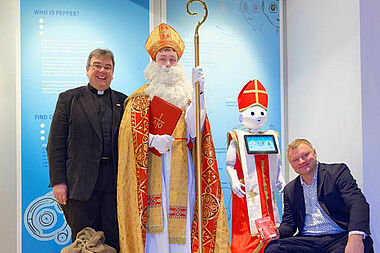 Verkleidet als Nikolaus wird Roboter Pepper den Besuchern des HNF eine kleine Freude machen. Von Links: Monsignore Georg Austen, Bischof Nikolaus, Roboter Pepper und Jochen Viehoff. Foto: Jan Braun/HNF