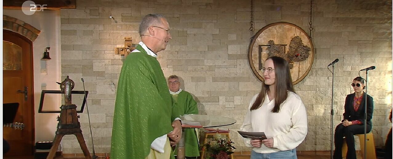 Vorne: Pater Christian Heim im Gespräch mit Miriam. Monsignore Georg Austen war der Hauptzelebrant des Gottesdienstes, die Schweizer Jazz- und Gospelsängerin Bernarda Brunovic zeichnete sich mit für die Musik verantwortlich. (Bildschirmaufnahme vom ZDF-Fernsehgottesdienst)