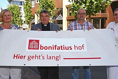 Den Bonifatiushof auf dem Parkplatz des Bonifatiuswerkes erreicht man über die Liboristrasse, eine der meist frequentierten Straßen zu Libori. Von Links: Karin Stieneke (Bereichsleiterin Kommunikation und Fundraising im Bonifatiuswerk), Monsignore Georg Austen (Generalsekretär Bonifatiuswerk), Ulrich Schulte (Almetalküche) und Schwester Theresita (Redakteurin im Bonifatiuswerk) laden ein zu einem Besuch auf dem Bonifatiushof. Foto: Patrick Kleibold