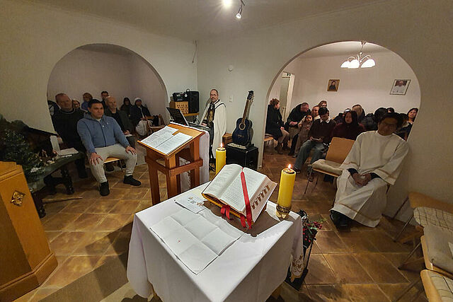 Die Besucherinnen und Besucher des Gottesdienstes sitzen in dem kleinen Wohnraum dicht gedrängt zusammen. (Foto: Diözese Reykjavík)