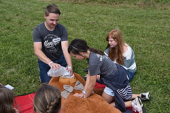 Sebastian und Luise (11) machen Milena (11) vor, wie eine Herzdruckmassage funktioniert. (Foto: Simon Helmers)