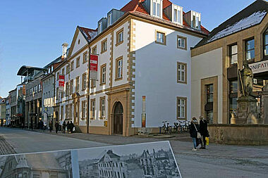 Das Gebäude am Kamp 22, das heutige Bonifatiushaus, wurde um 1720 erbaut. Die Tafel im Vordergrund zeigt eine Ansicht des durch Bomben zerstörten Gebäudes nach dem 2. Weltkrieg, das in den Jahren 1947-49 durch das Bonifatiuswerk wieder aufgebaut wurde. Foto: Patrick Kleibold