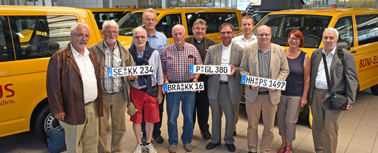 Monsignore Georg Austen (Mitte) übergab in Paderborn an die Vertreter von vier Kirchengemeinden und Institutionen aus den Erzbistümern Hamburg und Berlin und dem Bistum Münster einen rapsgelben BONI-Bus. Foto: Lena Reiher