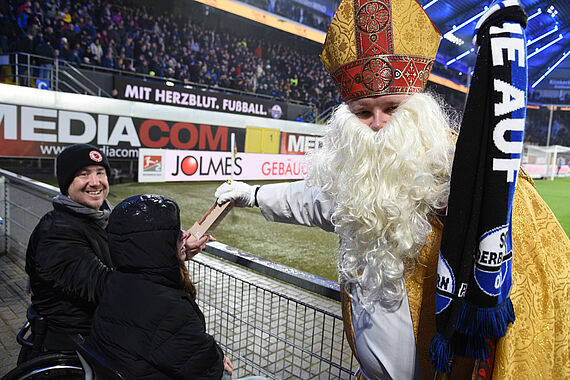 Bischof Nikolaus verteilt Schokonikoläuse des Bonifatiuswerkes an die Fußballfans. (Foto: Theresa Meier) 