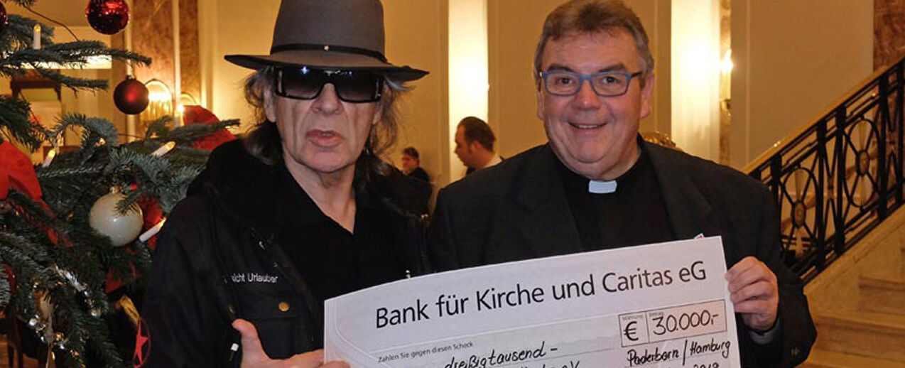 Udo Lindenberg und Monsignore Georg Austen präsentieren den Scheck in Höhe von 30.000 Euro, der an drei soziale Projekte für Frauen und Kinder übergeben wird. (Foto: Bonifatiuswerk) 