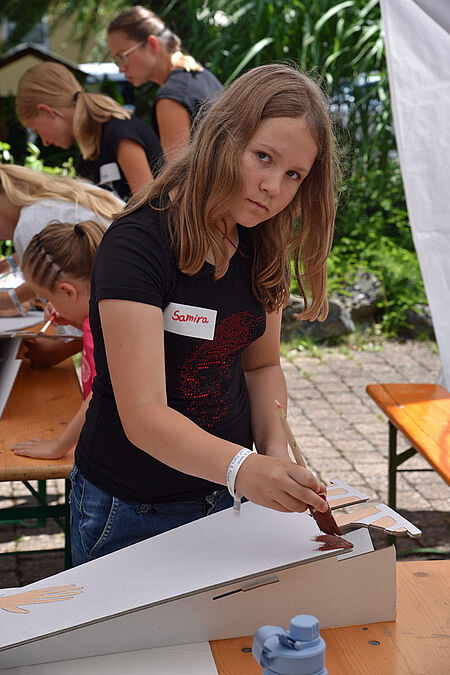 Mit brauner Farbe bemalt Samira (10) das Gewand vom Klara-Pappaufsteller. (Foto: Simon Helmers)