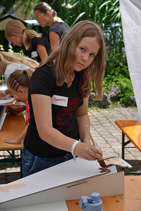 Mit brauner Farbe bemalt Samira (10) das Gewand vom Klara-Pappaufsteller. (Foto: Simon Helmers)