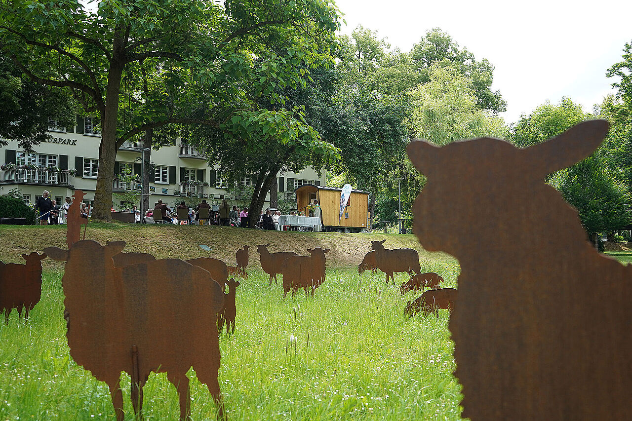 Mit einem Gottesdienst wird der Schäferwagen im Kurpark eingeweiht. Die Herde aus Cortenstahl erinnert an die Entdeckung der Heilquelle. (Foto: DRS/Guzy)